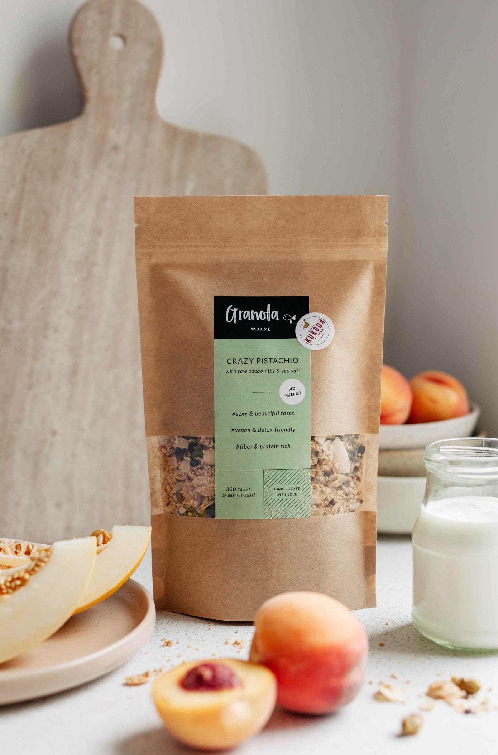 w opakowaniu na stole granola z pistacjami, syropem klonowym, płatkami migdałowymi i kokosowymi