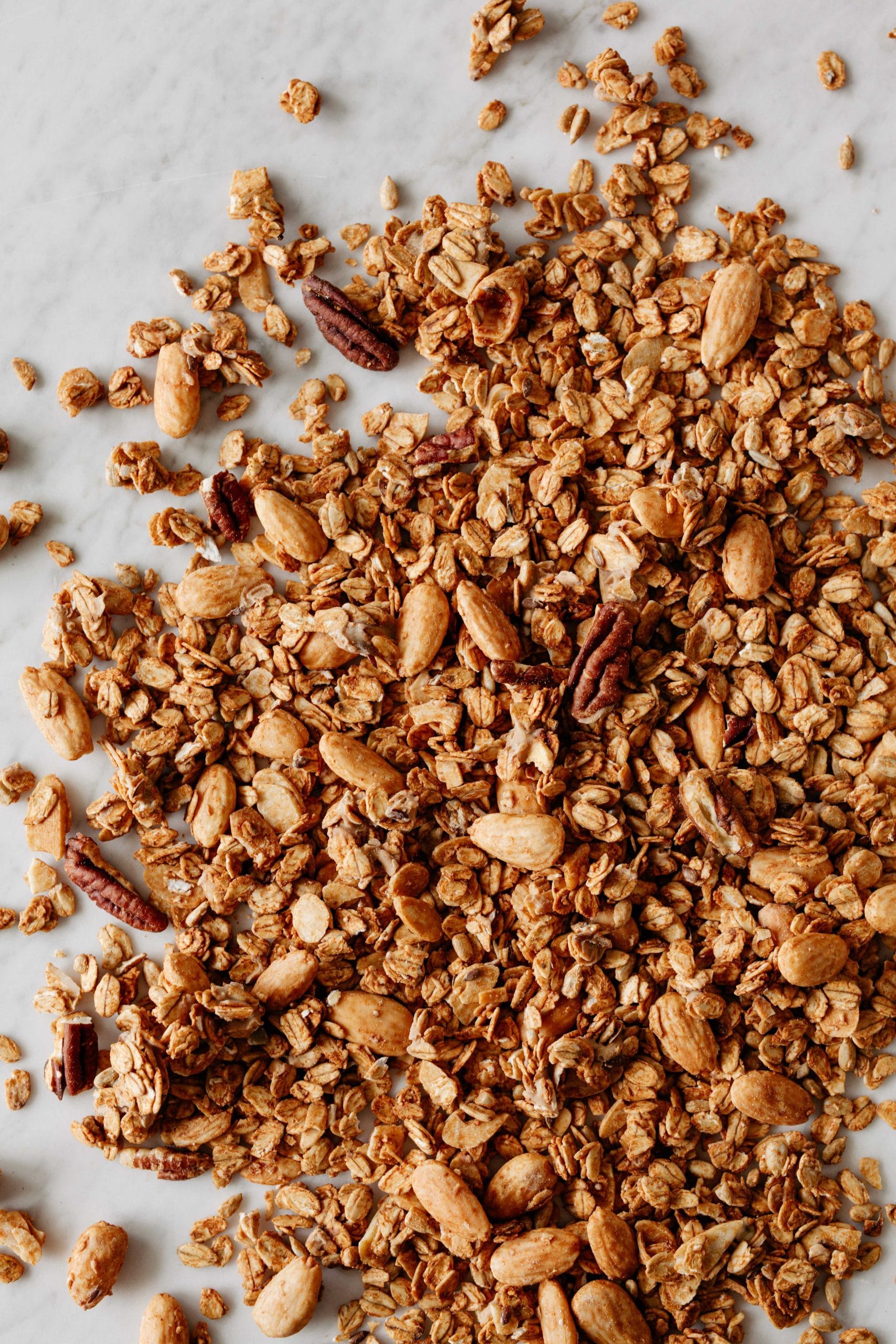 Widoczne orzechy pekan i migdały blanszowane oraz płatki owsiane opiekane w kajmaku.